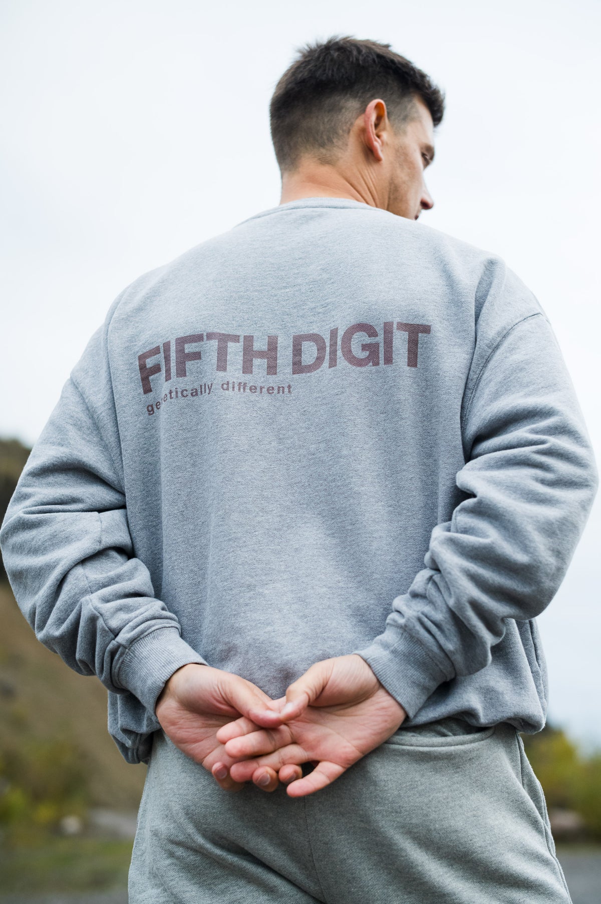 Model wearing Fifth Digit Arch 460gsm crewneck in grey marl, back view with burgundy print