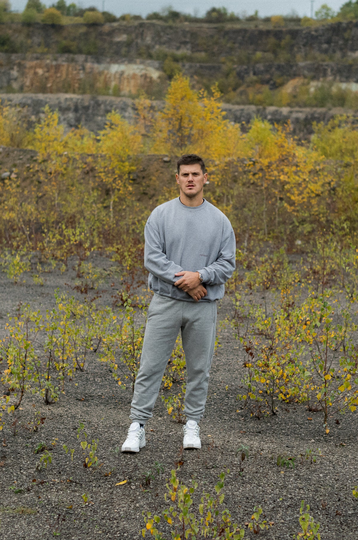 Model wearing Fifth Digit Arch 460gsm crewneck in grey marl, standing in a quarry