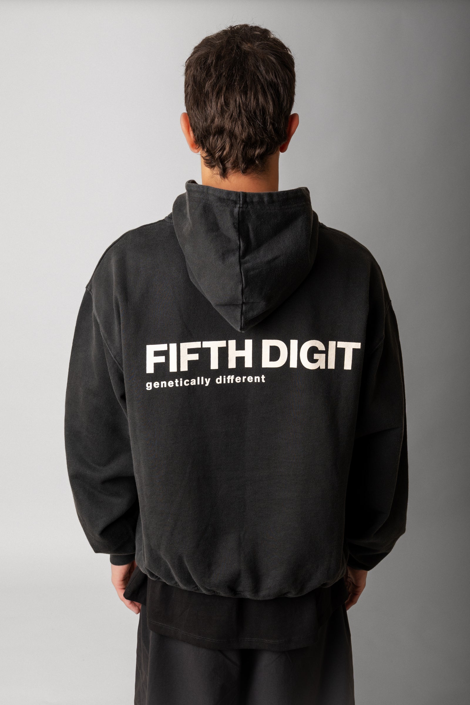 Model wearing Fifth Digit Frame 460gsm organic cotton hoodie in vintage black, back view with graphic print