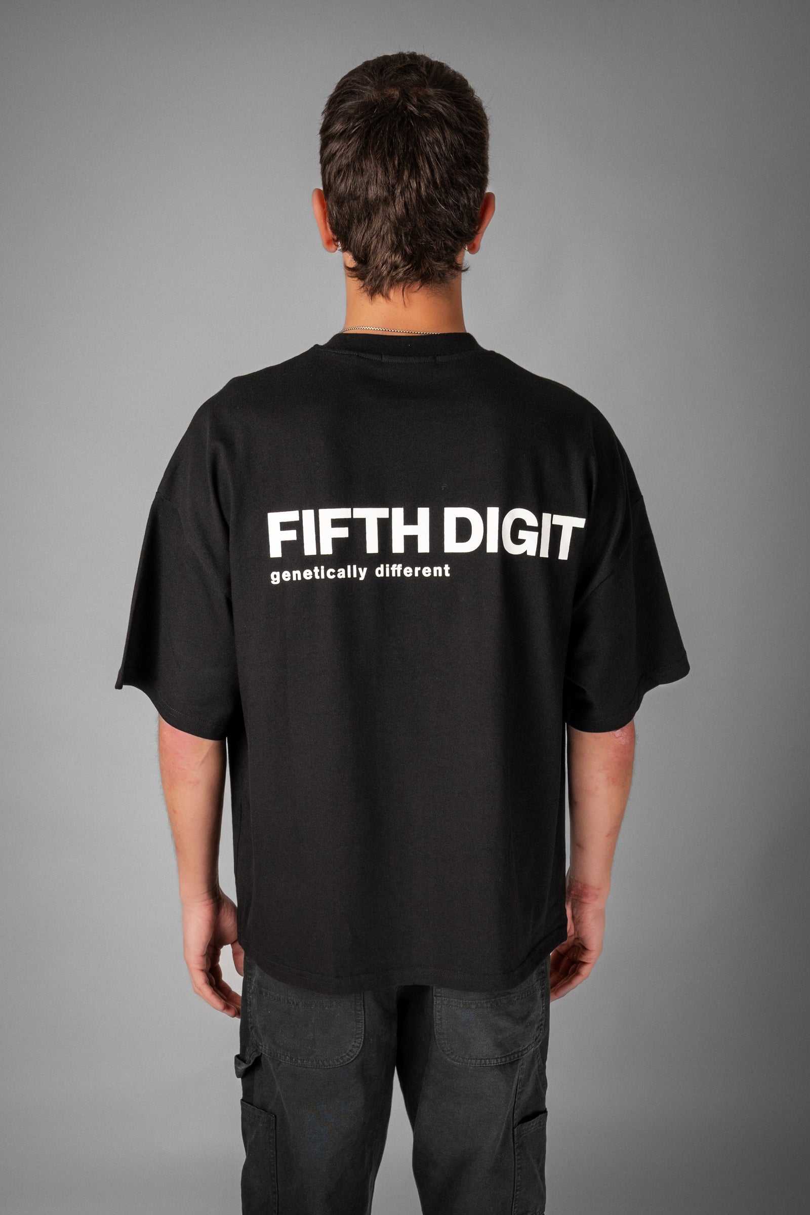 Model wearing Fifth Digit Pressure 240gsm organic cotton tee in black, back view with graphic print