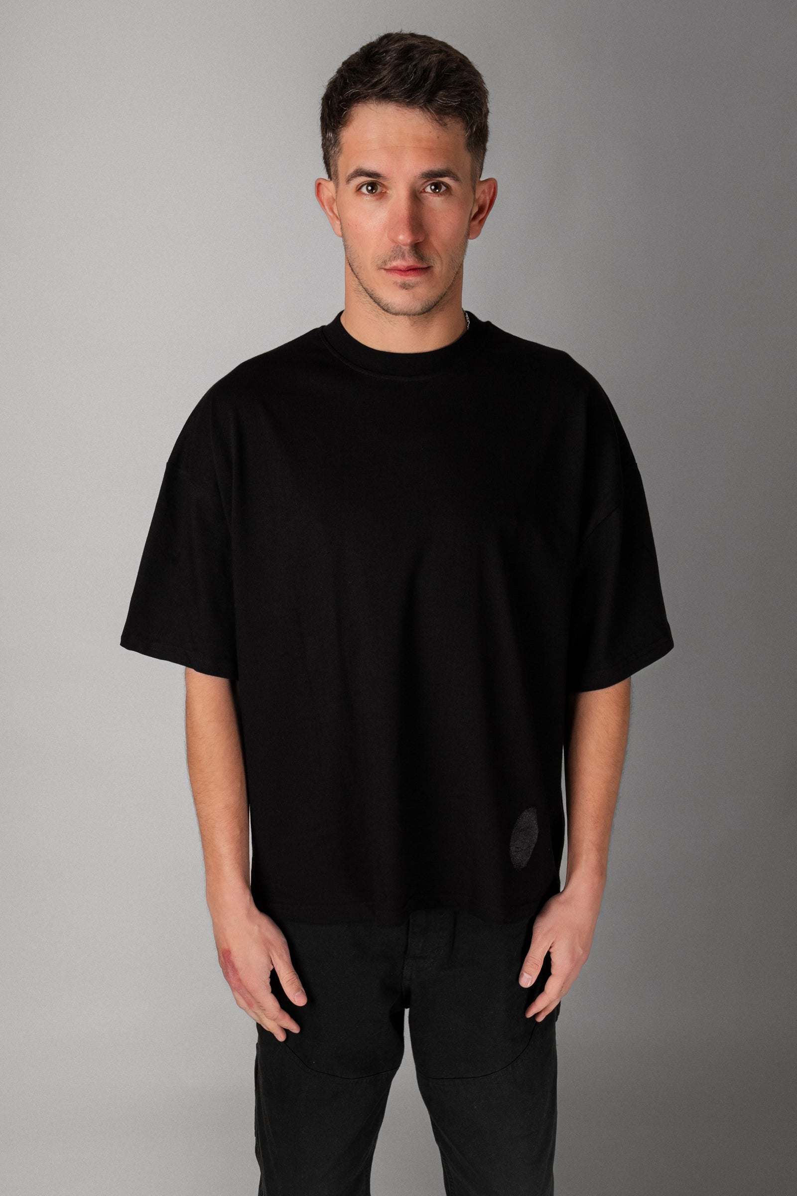 Model wearing Fifth Digit Pressure 240gsm organic cotton tee in black, front view