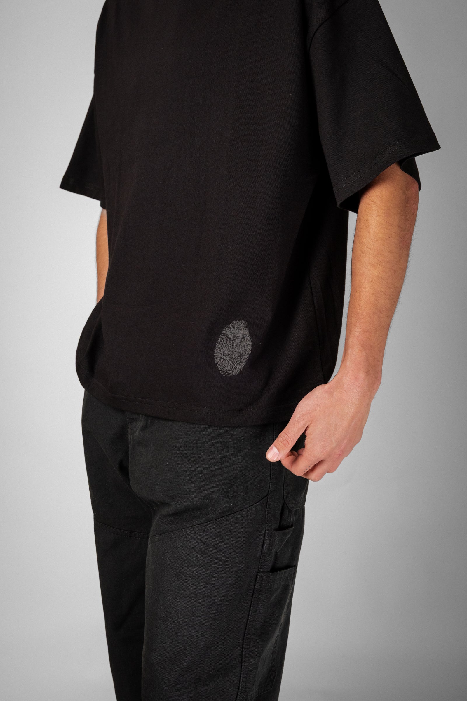 Model wearing Fifth Digit Pressure 240gsm organic cotton tee in black, side view