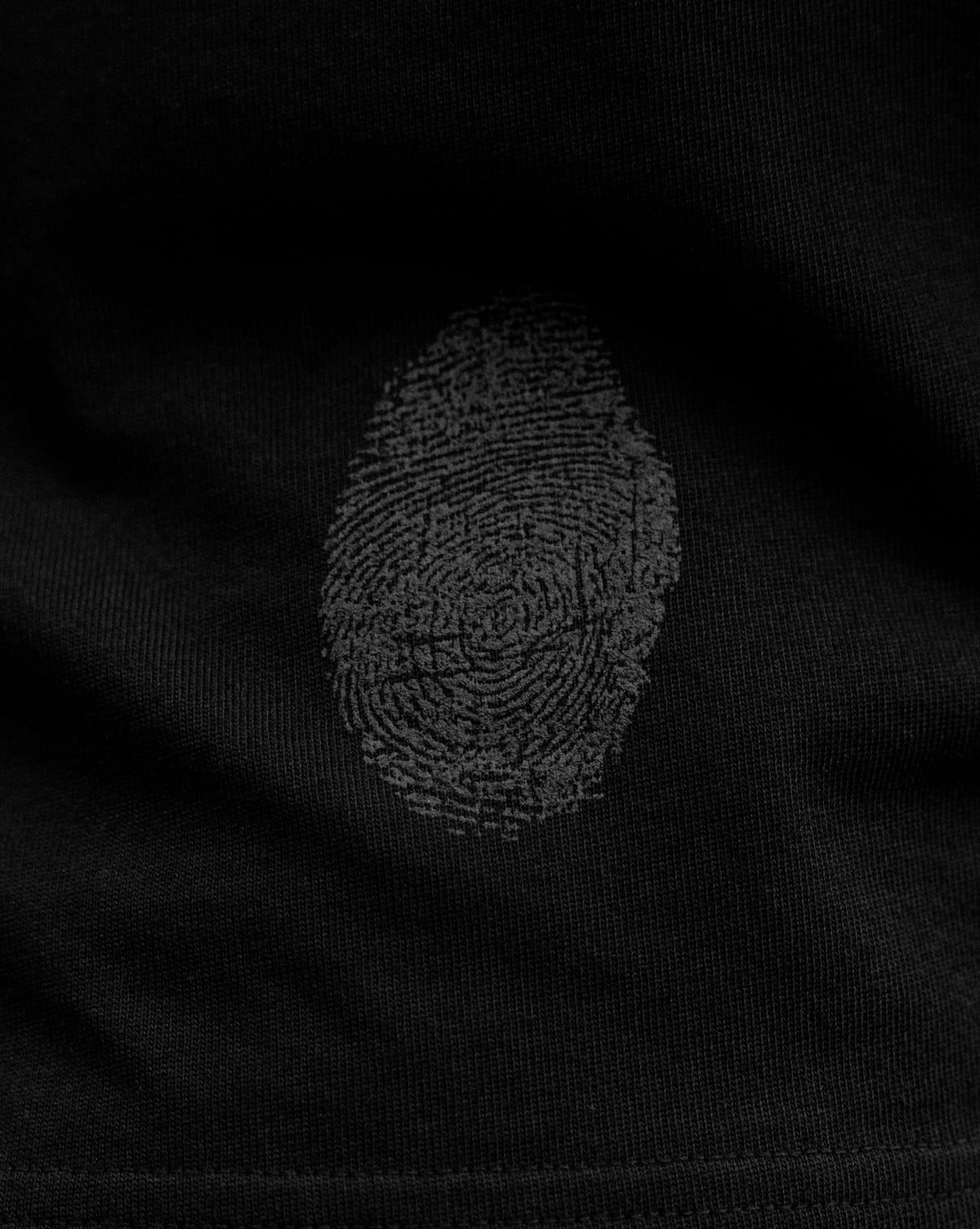 Close detail of the Fifth Digit thumbprint screen print on the Pressure 240gsm organic cotton tee in black